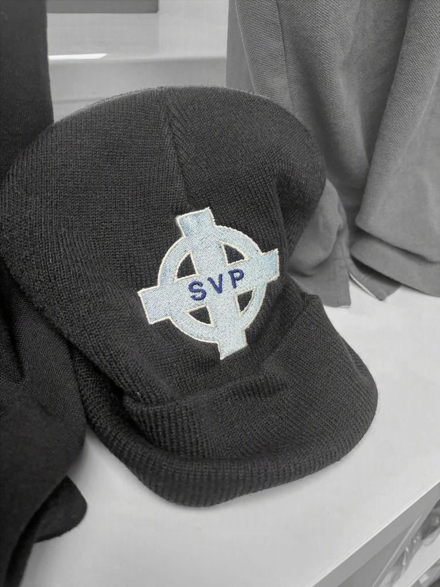 Black flat cap with SVP cross logo embroidered in light blue by SVP Southend Embroidery